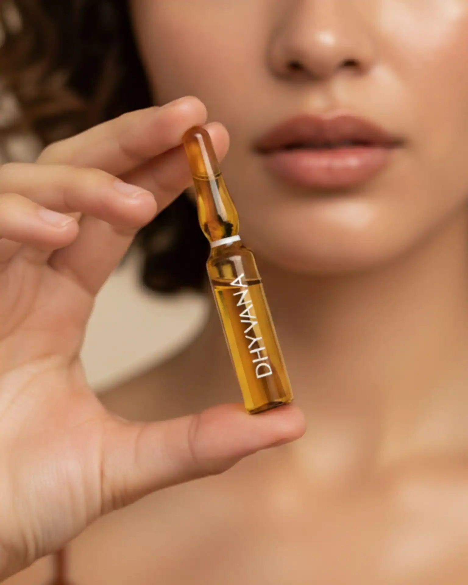 Woman holding a DHYVANA facial ampoule, visualizing a strategic investment in rigorous, bio-mimetic skincare formulas.